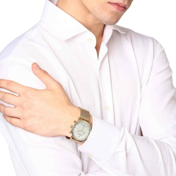 Gold chronograph watch with cream dial worn on wrist over white shirt
