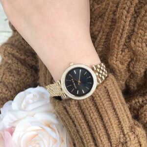 Michael Kors Darci gold watch on wrist showing black dial and crystal bezel