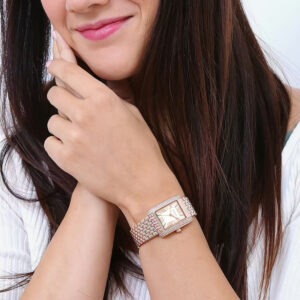 Michael Kors Emery Pavé rose gold-tone watch worn on woman's wrist showing rectangular face and link band