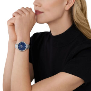 Michael Kors Pyper blue dial watch worn on woman's wrist with silver metal band