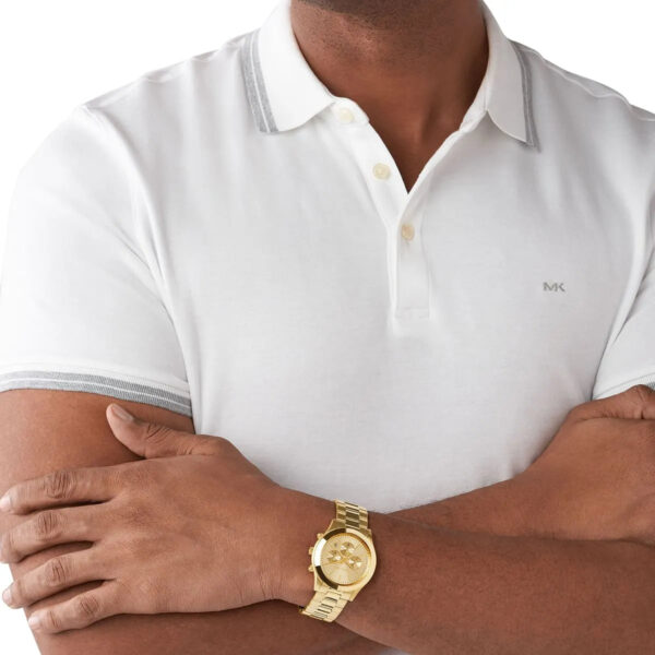 Michael Kors MK8909 gold chronograph watch worn on wrist with white polo shirt
