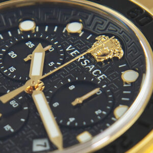 Close-up of Versace Greca Dome black dial with gold chronograph hands, Medusa logo, and hour markers